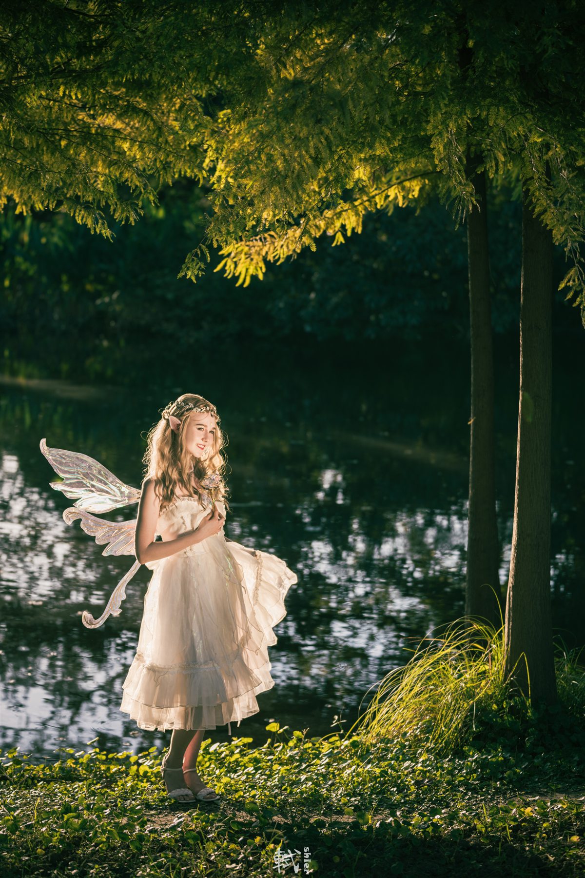 A full-length elf portrait standing by dark green water and foliage