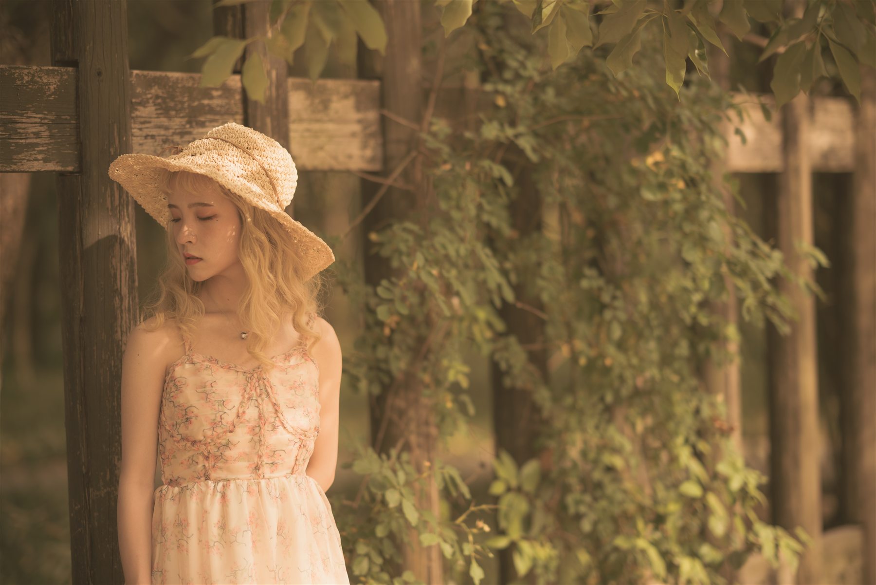 A warm portrait in a straw hat standing among leaves and wood textures